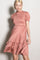 woman wearing a blush pink short sleeve smocked dress with a tiered skirt and ruffled hem