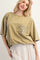 woman wearing an olive green oversized t-shirt with a crochet pocket detail and a flowy polka dot skirt