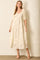 woman wearing a cream puff sleeve maxi dress with floral details and a v-neckline, standing against a textured wall