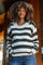 woman wearing a black and white striped maternity sweater with a visible baby bump and casual blue jeans