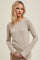 woman wearing a beige long sleeve ribbed top, styled with a round neckline and fitted silhouette