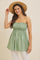 woman wearing a light green strapless smocked top with a flared silhouette and a straw hat