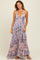 woman wearing a flowy pink paisley maxi dress with a halter neckline and ruffled hem