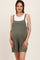woman wearing a green maternity romper with a pocket, showing her baby bump