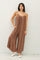 woman wearing a brown striped spaghetti strap jumpsuit with wide legs and pockets