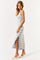 woman wearing a light blue and white striped maxi dress with a side slit and spaghetti straps, standing in profile