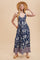 woman wearing a navy blue floral maxi dress with a v-neckline and a patterned hem, paired with a straw hat