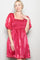 woman wearing a bright pink puff sleeve mini dress with a smocked bodice and flowing skirt