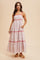 woman wearing a white patterned maxi dress with red detailing and pockets, posing against a neutral background