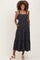 woman wearing a black floral print maternity dress with tie straps and pockets, showcasing a baby bump