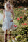 woman wearing a white floral sundress with a smocked bodice and pockets, paired with brown cowboy boots in a garden setting