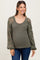 woman wearing a green maternity top with embroidered long sleeves and a rounded neckline, showcasing her baby bump