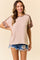 woman wearing a light pink short sleeve top with leopard print accents and distressed denim shorts
