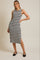 woman wearing a black and white striped sleeveless midi dress with side slit and black flat shoes