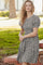 woman wearing a black and white floral puff sleeve dress, standing outdoors with a grassy background