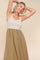 woman wearing a striped sleeveless dress with a beige skirt and a fitted bodice, smiling and posing with her arms raised