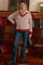 woman wearing a red and white striped maternity sweater with a v-neck and long sleeves paired with jeans and smiling
