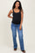 woman wearing a black maternity tank top and blue jeans, smiling with a visible baby bump