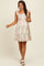 woman wearing a white floral maternity dress with ruffled straps and a fitted bodice, holding her baby bump