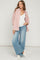woman wearing a pink striped oversized button-up shirt and light blue wide-leg jeans, showing her baby bump