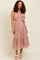 woman wearing a floral print maternity dress with ruffle details and a tie waist, styled with sandals