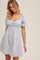woman wearing a light blue checkered puff sleeve mini dress with a sweetheart neckline and gathered waist