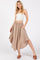 woman wearing a beige button-up maxi skirt with an elastic waistband and pockets, paired with a white cropped top