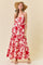 woman wearing a red and white floral maxi dress with thin straps and a wide-brimmed hat