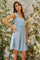 woman wearing a light blue floral print sundress with a square neckline and thick straps