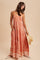 woman wearing a red patterned maxi dress with pockets and holding a straw hat