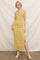 woman wearing a yellow ribbed maxi dress with textured stripes and a side slit, standing against a neutral backdrop
