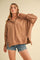 woman wearing a brown oversized pullover sweatshirt with a collar and button details, styled with denim shorts