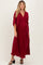 woman wearing a burgundy maternity dress with a v-neck and flowy sleeves, highlighting a baby bump