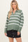 woman wearing a green and white striped long sleeve sweater with a collared neckline and black button-front skirt
