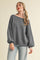 woman wearing a gray ribbed oversized sweater with balloon sleeves and off-the-shoulder neckline, paired with light blue jeans