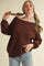 woman wearing a brown off-the-shoulder knit sweater and holding her hair with two hands