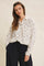 woman wearing a cream floral long sleeve button-up shirt with a chest pocket and loose black pants