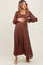 woman wearing a brown maternity maxi dress with long sleeves, a tie waist, and a visible baby bump
