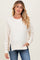 woman wearing a cream-colored maternity sweatshirt with side slits and a relaxed fit, styled with blue jeans