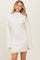 woman wearing a cream ribbed long sleeve mini dress with a high neckline and flared sleeves