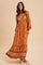 woman wearing a long sleeve bohemian floral maxi dress in orange and brown tones with a flowy skirt