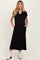 woman wearing a black maternity dress with a v-neck and pom-pom trim, standing with hands in pockets