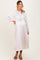 woman wearing a light pink pleated maternity dress with long sleeves and a gathered waist, showing her baby bump