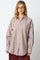 woman wearing a brown and white striped oversized button-up shirt with a front pocket and long sleeves