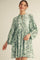 woman wearing a green floral print mini dress with long sleeves and a keyhole neckline