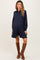 woman wearing a navy striped maternity shirt dress with a flared hem and brown knee-high boots, showing her baby bump