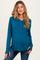 woman wearing a teal maternity long sleeve henley top with button detail and a visible baby bump