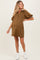 woman wearing a brown maternity dress with puff sleeves and a zippered collar, showing her baby bump