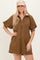 woman wearing a brown short sleeve zip-up dress with puff sleeves and a collar