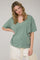 woman wearing a green oversized v-neck top with relaxed sleeves and subtle stitching details